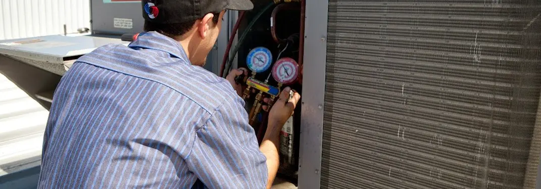 HVAC technician servicing a condenser unit in Fort Collins